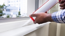 Close-up Of Person Hand Applying Silicone Sealant With Silicone Gun On Window Close-up Of Person Hand Applying Silicone Sealant With Silicone Gun On Window