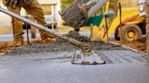 Construction workers are spreading cement mixture on the ground
 