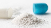 An open medicine capsule with white powder in the foreground. An open medicine capsule with white powder in the foreground.