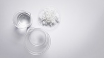 Crystal clear liquid in beaker, Flake salt in Chemical Watch Glass. Chemicals ingredients on  laboratory table. Top View Crystal clear liquid in beaker, Flake salt in Chemical Watch Glass. Chemicals ingredients on  laboratory table. Top View