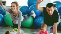 Two adults and their toddlers exercising on a yoga mat