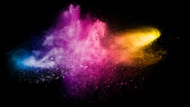 Explosion of colorful Holi powder on black background. Vibrant color dust particles textured background.