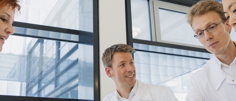 Four BASF scientists in white lab coats talking.