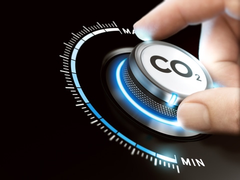 Man turning a carbon dioxyde knob to reduce emissions. CO2 reduction or removal concept. Composite image between a hand photography and a 3D background.